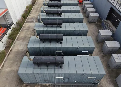 Industrial power generators lined up at facility Stock Photos