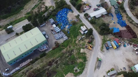 Industrial recycling complex with blue barrels and heavy vehicles in hills 動画素材 344095760