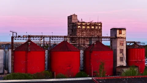 Industrial red grain elevator silos and towers at sunset with a pink sky Stock Footage 340282262