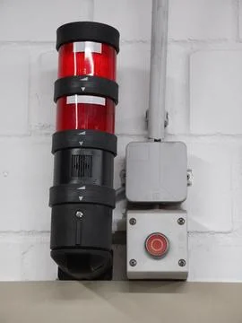 Industrial red warning beacon with emergency stop button mounted on white b.. Stock Photos