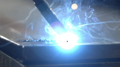 Industrial robotic welding arm creating bright blue sparks on metal plate d.. Stock Footage 337543405