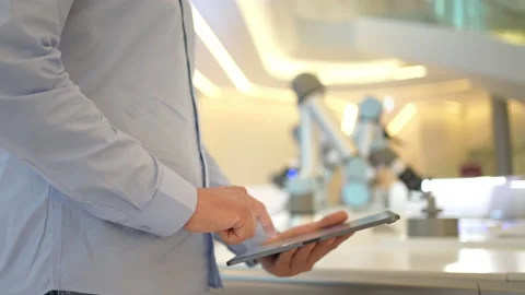 Industrial robotics engineer man using tablet, futuristic robot arm. Factory Stock Footage 170476746