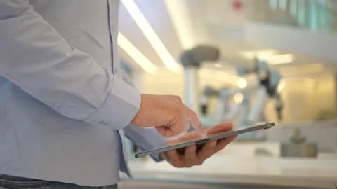 Industrial robotics engineer man using tablet, futuristic robot arm. Factory Stock Footage 170476863