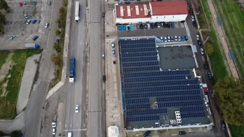 Industrial rooftop covered with solar panels beside busy urban road Stock Footage 343994632