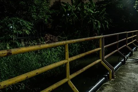 Industrial rust texture on iron railing infrastructure over canal at nigh Stock Photos