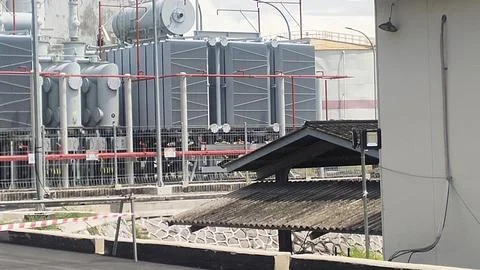 Industrial scene featuring large transformers and a shelter in an electrica.. Photos
