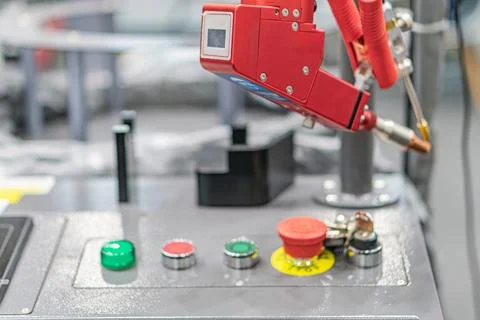 Industrial setting with red robotic arm above a control panel, artificial lig Stock Photos