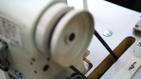 An industrial sewing machine driven by a belt stops. The belt worn on the pulley Stock Footage 195023683
