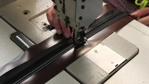Industrial sewing machine stitching a black zipper Stock Footage 338188815
