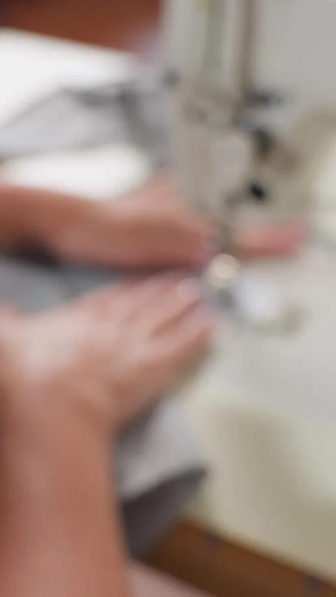 Industrial sewing machine stitching grey fabric, caucasian operator guiding Stock Footage 323808651