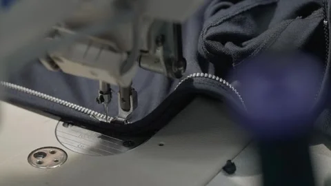 Industrial sewing machine stitching zipper onto fabric Stock Footage 331985070