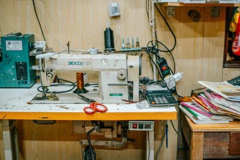 Industrial sewing machine on a worktable inside a traditional tailoring workshop Stock Photos