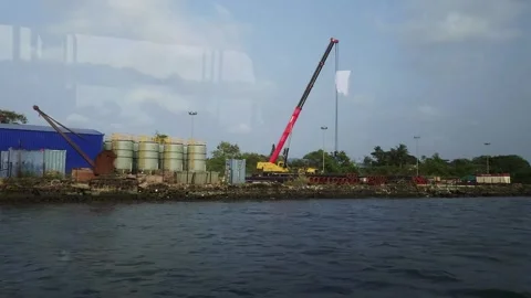 Industrial shoreline development with mobile crane operating alongside storage t Stock Footage 344628380
