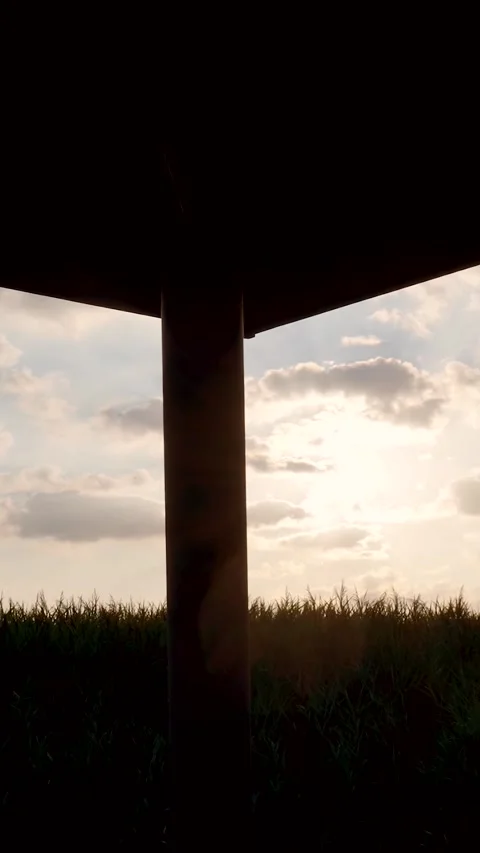 Industrial silhouetted structure at sunset over a green field Stockbeeldmateriaal 327111817