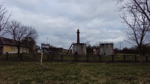 Industrial site with structures and chimney in an open area during cloudy weathe Stock Footage 337125471