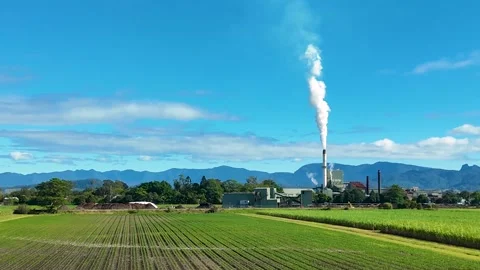 Industrial Smoke Stack Billowing Over Green Farmland and Distant Mountains Stock Footage 326081042