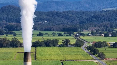Industrial Smoke Stack Emitting White Vapor Over Rural Green Farmland Stock Footage 325691868