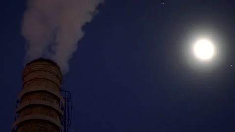 Industrial smoke stack spewing steam into the air on a moonlit night Stock Footage 144472613
