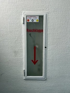 Industrial smoke vent control panel with German warning sign on textured wall Photos