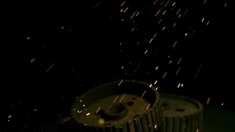 Industrial sparks falling and bouncing off rusty metal gears Stock Footage 327789604