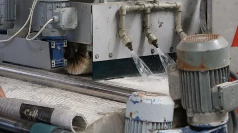 Industrial stone cutting machine spraying cooling water onto stone slab during Stock Photos