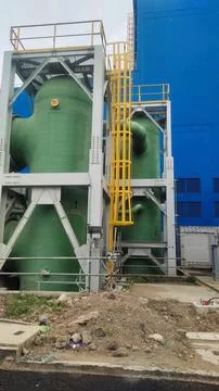 Industrial structure featuring large green tanks and yellow safety railings. Photos