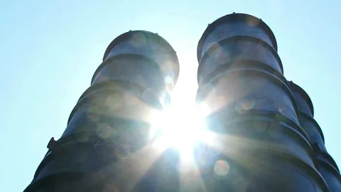 Industrial Structures Silhouetted Against Bright Blue Sky with Sun Flare Stock Footage 330675492