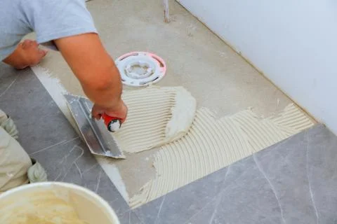 Industrial tiler builder worker installing floor tile Foto stock