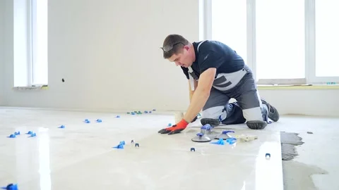 Industrial tiler Professional builder worker installing floor a large ceramic Stock Footage 143764090