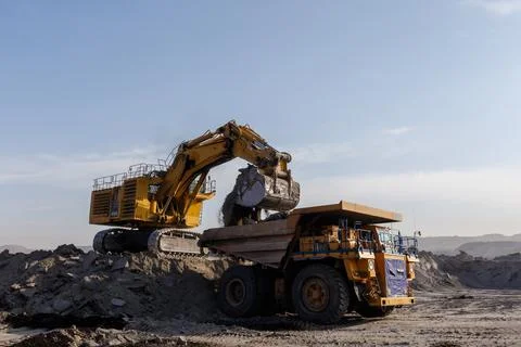 Industrial work in an open pit coal mine. Close-up. A large excavator pours s Stock Photos