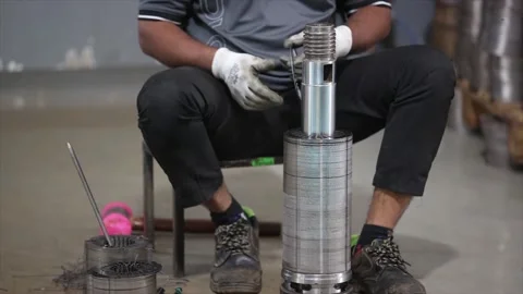 An industrial a worker assembling a heavy mechanical component by hand while Stock Footage 328387088