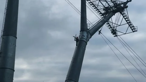 Industrial worker climbing large high altitude electrical tower Stock Footage 342024457