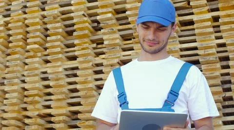 Industrial worker in uniform checking large wooden box on tablet in warehouse Stock Footage 57095397