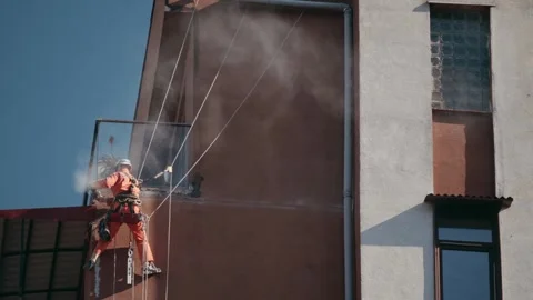 Industrial worker using angle grinder on high-rise building. Professional Stock Footage 303646562