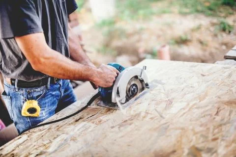 Industrial worker Using Circular Saw on wooden board in Carpentry Workshop Stock Photos
