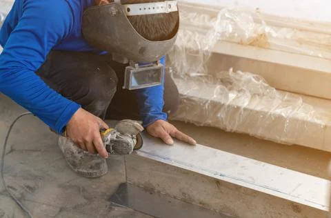 Industrial worker using an grinder for cutting stainless frame. Stock Photos