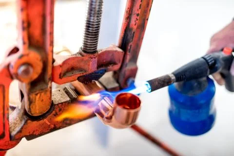 Industrial worker using propane gas torch for soldering copper pipes. Stock Photos