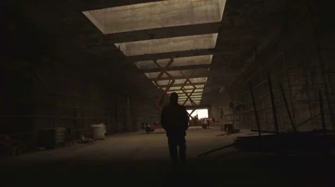 An industrial worker walks through a dark tunnel Stock Footage 64554693