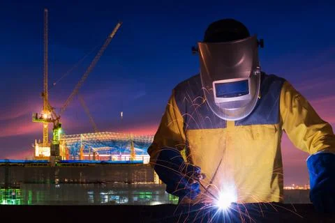 Industrial worker welding steel structure for infrastructure building project Stock Photos