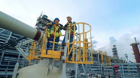 Industrial workers and engineers standing on tower front of large factory Stock Footage
