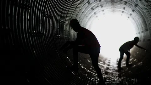 Industrial workers silhouettes inside a huge pipe Stock Footage 236710391