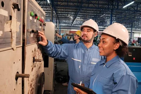 Industry engineers inspect machine control panels in manufacturing factory. Stock Photos