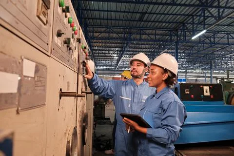 Industry engineers inspect machine control panels in manufacturing factory. Stock Photos