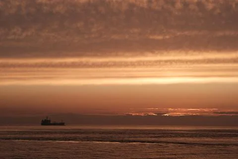 Industry ship driving into dramatic ocean sunset Stock Photos