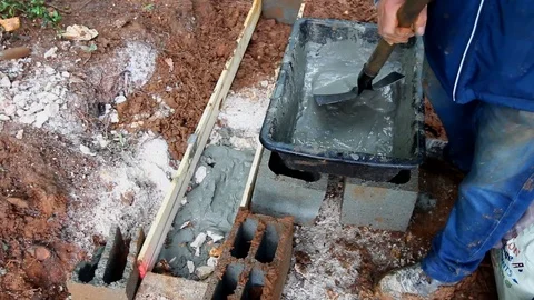 Industry worker pouring liquid cement in a trench with a shovel. Stock Footage 109250976