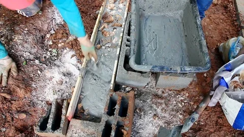 Industry worker spreading out cement into a trench. Stock Footage 109379717