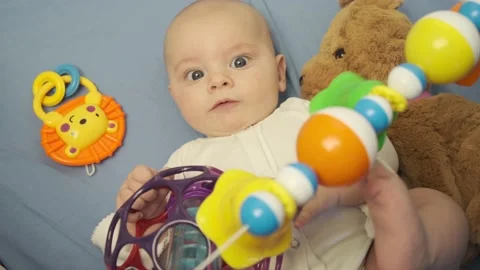 Infant baby boy playing with developing toys lying in bed. Top view. Stock Footage 138670401