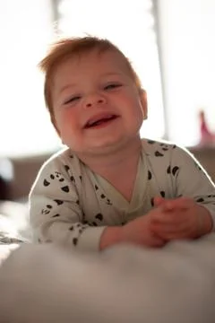 Infant in bed with first teeth smiling Stock Photos