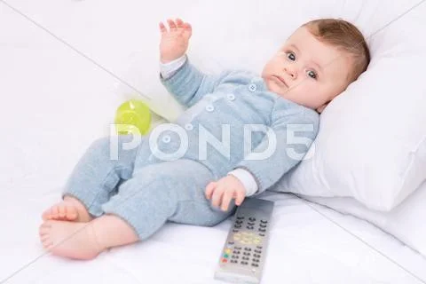 Infant boy with bottle and remote control Stock Photos