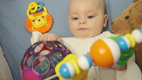 Infant boy playing with developing toys lying in bed. Top view. Stock Footage 138676027